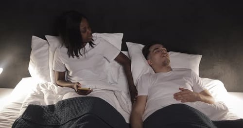 Couple multiethnique couché au lit ensemble. La femme ne peut pas coucher avec son mari parce qu'il