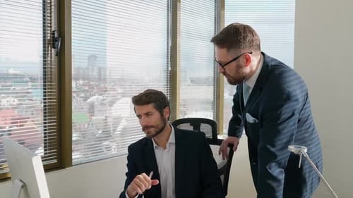Businessmen Collaborating Over Computer in Bright Office