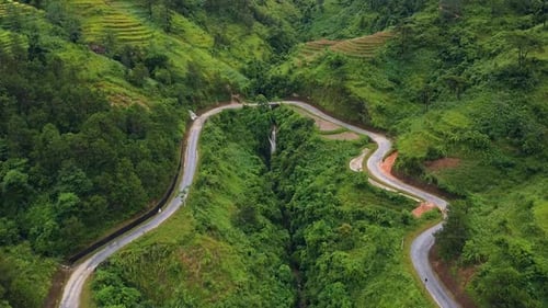 A Winding Road in the Mountains with Lush Greenery, Waterfall and Rice Terraces.