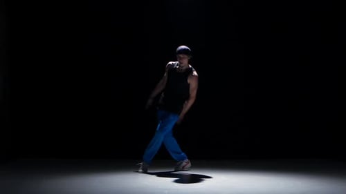 Junger Tänzer-Mann tanzt Breakdance auf Schwarz