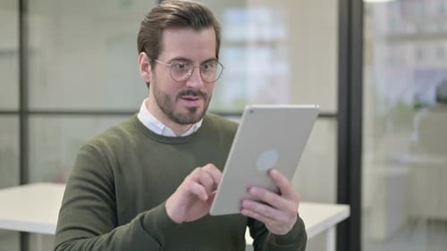 Young Businessman Celebrating on Tablet in Office