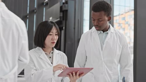 Scientists Discussing Data on Tablet in Modern Workplace