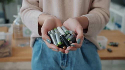Woman Holding Used Batteries for Recycling