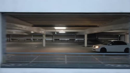 Drone shot of a car driving in a dark multi-story carpark