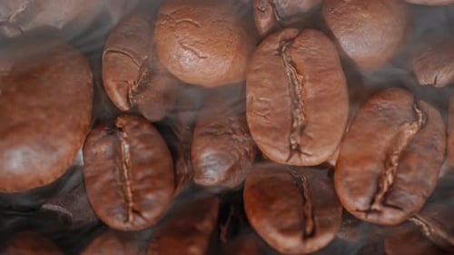 Primer plano de semillas de café. Los fragantes granos de café son tostados, el humo proviene de los granos