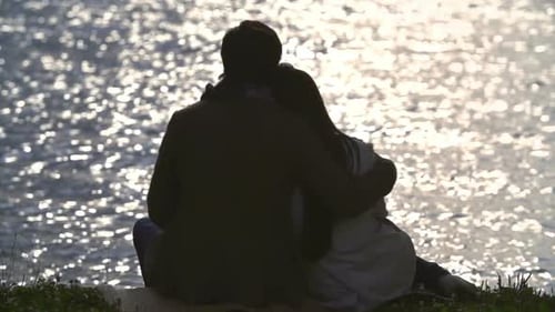 Couple Embrace Overlooking Sparkling Water at Sunset