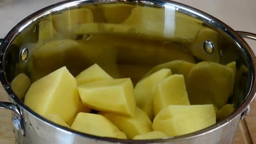 O chef coloca grandes pedaços de batata crua em uma panela e despeje com água fria e limpa
