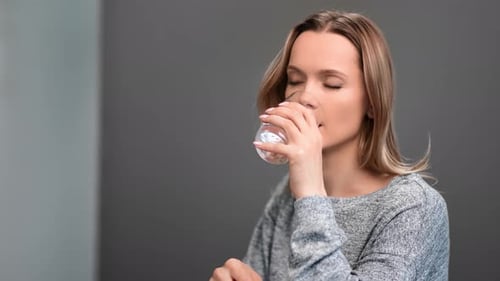 Woman Taking Pill with Glass of Water