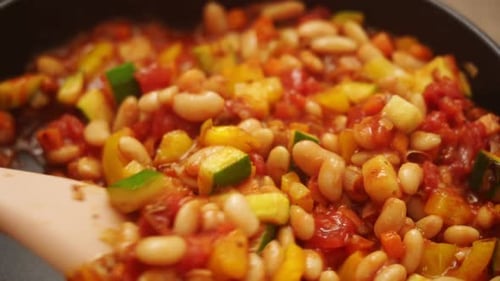 Vegetables and Beans Cooking in Pan with Wooden Spoon