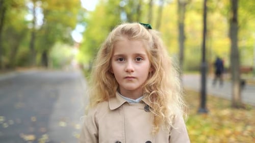 the Portrait of a Child Girl is in the Park Looking at Camera