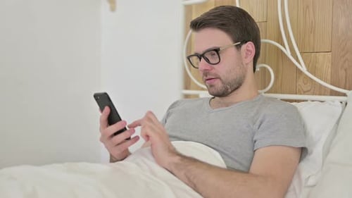 Man in Bed Uses Phone