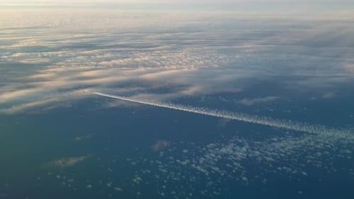 Incredible view from the cockpit of an airplane flying high above the clouds leaving a long white co