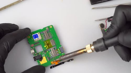 der Master-Lötkolben verlötet die Handyplatine mit einem Lötkolben