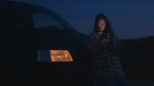 Woman Using Mobile Phone by Van at Night