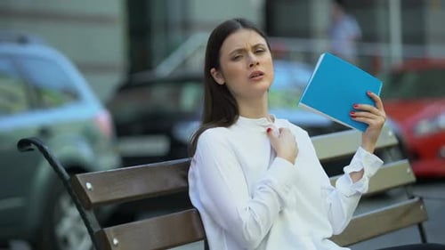 Woman Fanning Herself on Park Bench