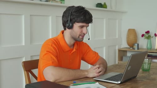 Man Uses a Headset To Talk Online at His Workplace Confident Man Sits at the Office Desk and Looks