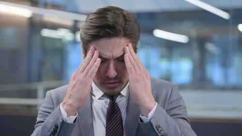 Stressed Businessman Rubbing Temples in Pain