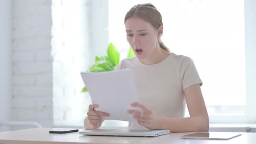 Woman Upset While Reading Documents in Office