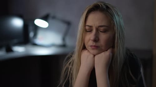Pensive Woman with Dirty Hair Sits in Semidark Office