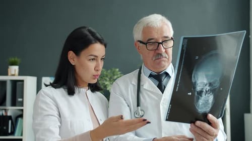 Female and Male Doctors Discussing X-ray Image of Skull Working in Clinic Together