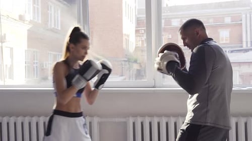 Female Boxer Practicing Hits with Her Personal Trainer in a Boxing Studio