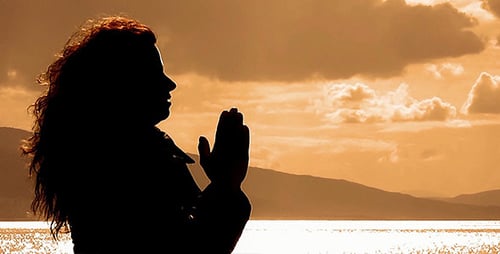 Silhouette of Praying Woman in Golden Sunset