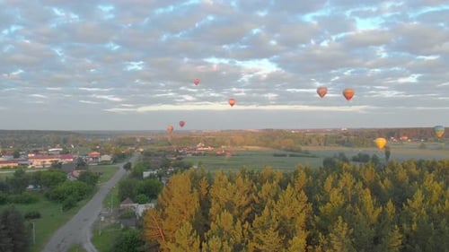 Hot Air Balloons Floating Over Rural Town at Sunrise