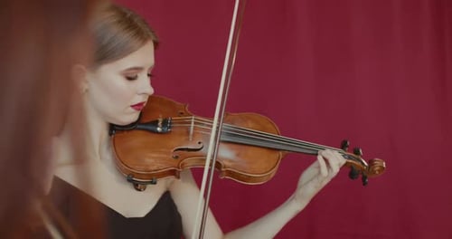 Close View of Female Musicians Duet Playing the Violins at Camera Indoor
