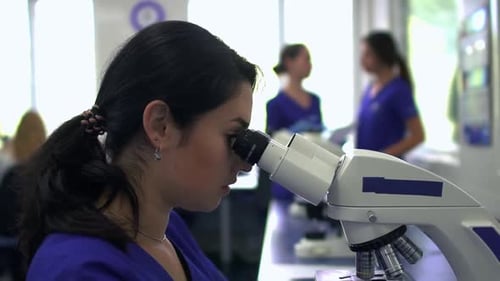 Young Pretty Woman Doing Analysis in the Laboratory Using Microscope Close Up. The Lady Looking