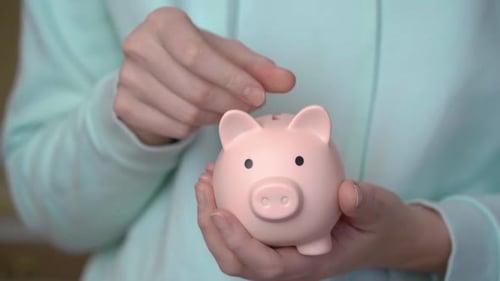 Female hand puts coins in a piggy bank. Money saving concept
