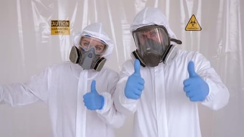 People in Protective Suits Give Thumbs Up