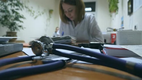 Jeune infirmière travaillant au bureau et rédigeant un stéthoscope de dossiers médicaux au premier plan