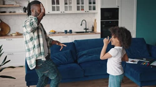 Cheerful Happy African American Father Dancing at Home with His Little Daughter Giving High Five to