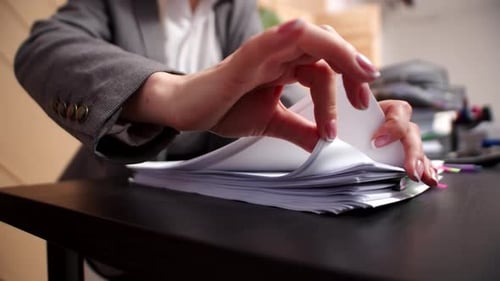 Closeup female hands of an office worker sorting through sheets from stack of documents. Female corp