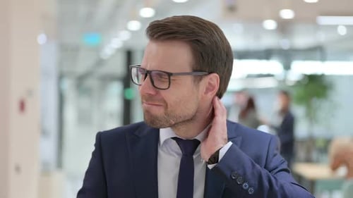 Stressed Businessman Experiencing Neck Pain at Office