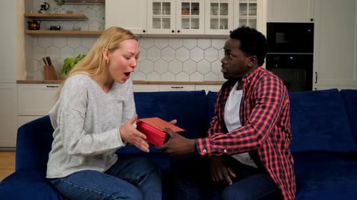 Man Gives Gift to Girlfriend on Blue Couch