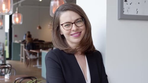Portrait of Young Smiling Businesswoman Standing in Modern Office Interior