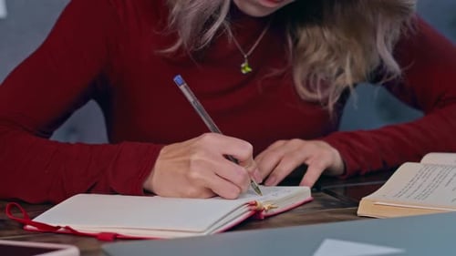 Eine junge traurige Studentin, überwältigt von Hausaufgaben, sitzt mit einem Laptop in einem Café