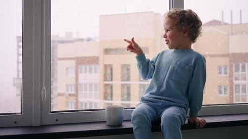 Curious Little Child is Looking Out Window and Amazing By Snow Christmas Miracle and Cozy Atmosphere