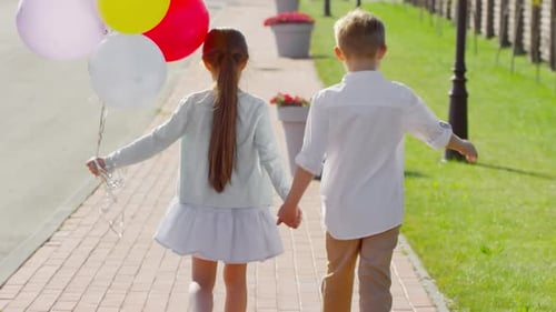 Kids Holding Hands and Walking with Balloons