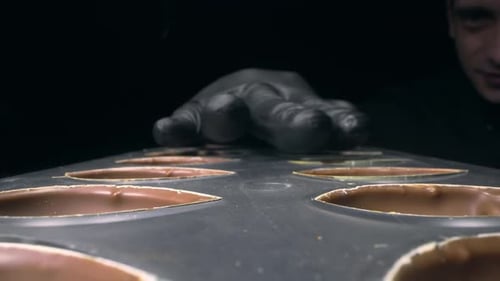 Gloved Hand Smoothing Chocolate into Mold