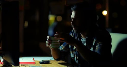 Bearded Man Working Late at Night Drinking Coffee