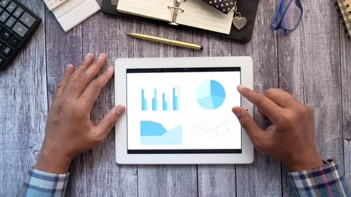 Man's Hand Working on Digital Tablet at Office Desk Using Self Created Chart