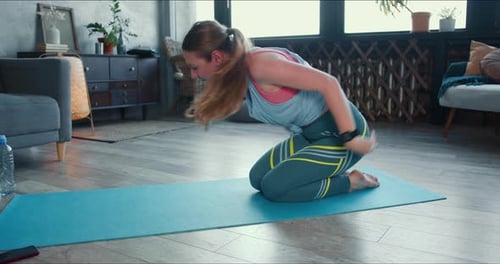 Woman Practices Yoga on Mat in Living Room