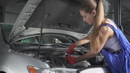 Experienced Mechanic Spinning with the Help of a Tool the Engine From an Auto Mechanic Is Repairing