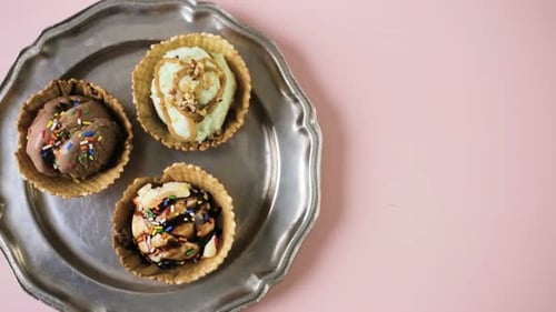 Waffeleisschalen mit Eiskugeln auf rosafarbenem Hintergrund.
