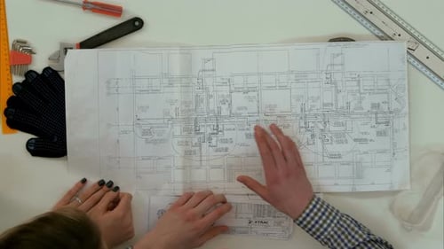Architects Analyzing Blueprints with Tools on a White Table