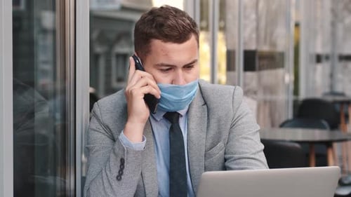 Freelance Businessman in a Mask Working in a Cafe