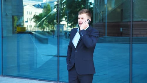 Handsome Businessman Talking on Phone Near Office and Celebrating Achievement
