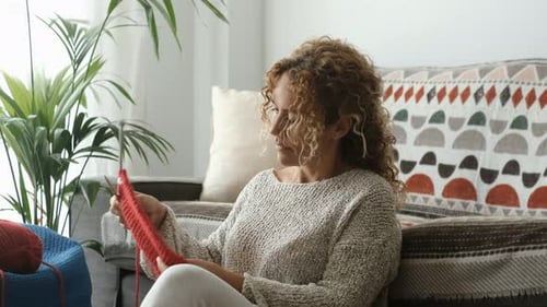 Woman Knitting with Red Yarn at Home